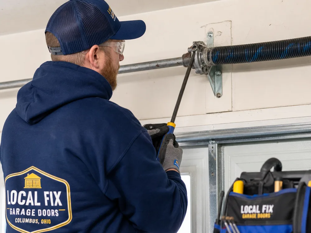 Technician safely checking a garage door torsion spring system and center bearing plate